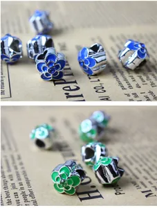 Vue détaillée des breloques fleur en argent avec émail bleu et vert et cristaux