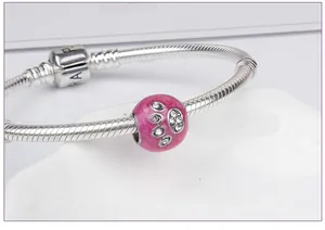 Detail of silver snake chain bracelet with pink enamel paw pendant and sparkling stones