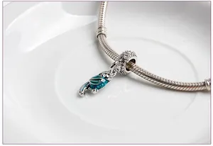 Macro shot of silver parrot pendant charm with blue enamel on a snake chain bracelet