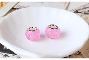 Close-up of pink resin candy beads with shimmering facets and silver metal core