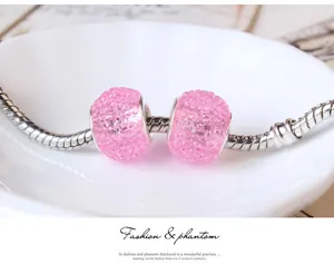 Macro view of pink crystal pavé cylinder beads on a silver snake chain jewelry