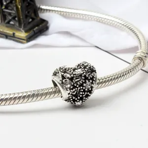 Detail van hartvormige bedel met fonkelende stenen op een slangenarmband