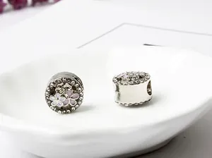 Makroaufnahme von silbernen Emaille-Blumenanhängern mit weißen Kristallen für DIY-Schmuck