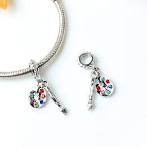 Macro shot of silver palette charm with colorful crystals and brush on snake chain