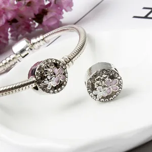 Makroaufnahme von Silber-Charm-Armband mit rosa Emaille-Blumen und weißen Kristallen