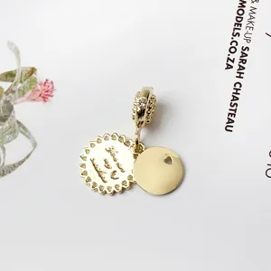 Détail d'un pendentif double disque doré avec cœur découpé et pierre sur la bélière