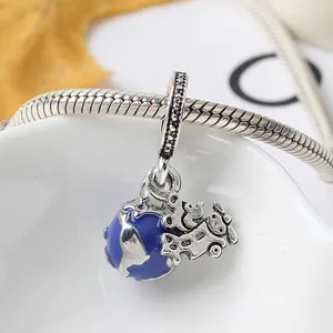 Nahaufnahme von silbernem Flugzeug- und blauem Emaille-Erdkugel-Anhänger am Armband