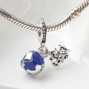 Makro-Detail von silbernem Erd-Anhänger mit blauer Emaille und Comic-Figur an Schlangenkette