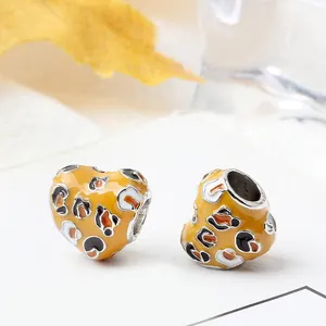Macro-opname van hartbedeltjes met luipaardprint en geel emaille voor DIY-sieraden
