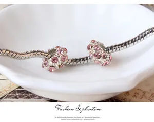 Detailaufnahme eines silbernen Schlangenarmbands mit zwei funkelnden rosa Kristallanhängern
