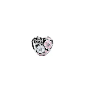 Macro view of heart-shaped hollow charm with pink enamel flowers and pavé zircon stones