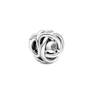 Charme en argent entrelacé avec une perle blanche centrale sur un fond blanc épuré