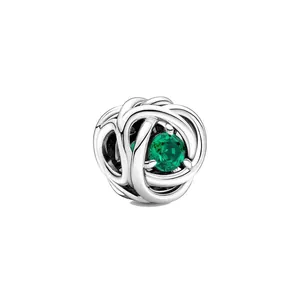 Détail macro d'une perle argentée entrelacée avec une gemme vert émeraude