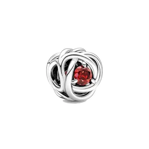Détail macro d'une perle en argent avec structure tissée creuse et pierre rouge