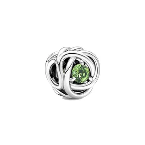 Gros plan d'un charm en argent avec pierre verte et design de noeud tressé