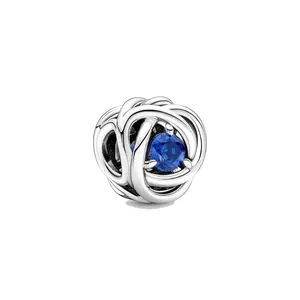 Gros plan d'un charm en argent au design entrelacé serti d'une pierre précieuse bleue