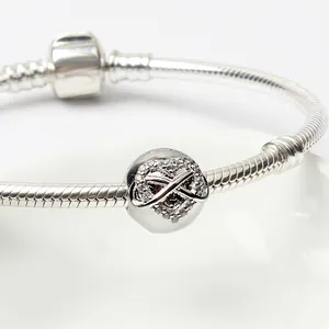 Dettaglio macro del bracciale a maglia snake in argento con charm cuore infinito e cristalli