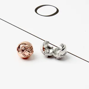 Dettaglio macro del charm cuore oro rosa con simbolo infinito e clip-on bead in argento