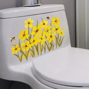 Detalle macro de un adhesivo floral amarillo para inodoro con abejas en cerámica blanca