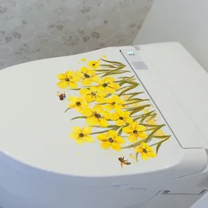 Detalle de pegatinas de PVC de flores amarillas y abejas en una tapa de WC blanca