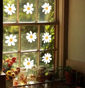 Detail showing seven white daisy window decals applied to a glass pane with sunlit background