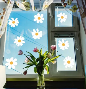 Detailed view of white daisy window stickers on glass with a clear blue sky background