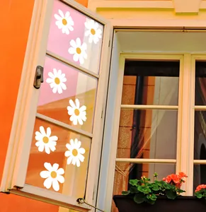 Detail of white daisy window stickers on a glass pane with a warm rustic background