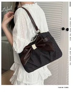 Detailed view of polka dot shoulder bag with large brown bow and lace edging
