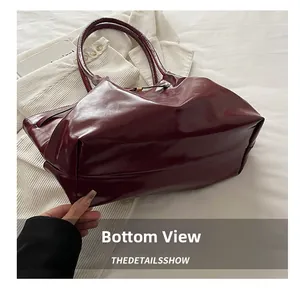Detailed bottom view of the burgundy tote bag with glossy leather texture on white fabric