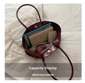Detailed interior of glossy burgundy bucket bag showing high capacity for tablets and umbrellas