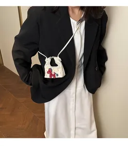 Detailed shot of white polka dot mini crossbody bag with red horse patch on a model