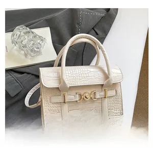 Detail of cream faux crocodile texture handbag with elegant gold metal buckle closure