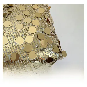 Gros plan de paillettes dorées de deux tailles sur le tissu en maille du sac
