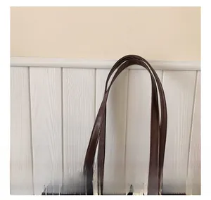 Detail of brown faux leather handle and lace trim on a black polka dot tote bag