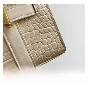 Detailed close-up of beige crocodile pattern leather and gold metal buckle hardware