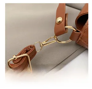 Detail of high-quality golden metal hook and buckle on brown leather shoulder bag strap