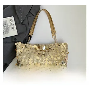 Détail du sac cabas à paillettes dorées avec bandoulière chaîne sur un livre de mode