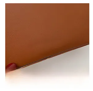 Close-up of caramel brown leather bucket bag featuring gold FASHION lettering and stitching