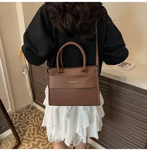Dettaglio della borsa tote marrone scuro con trama a coccodrillo e scritte dorate