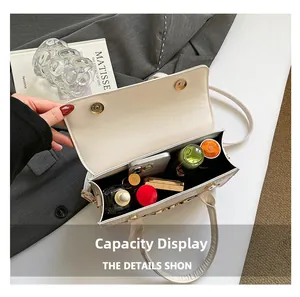 Interior capacity display of white croc-effect handbag showing phone and cosmetics
