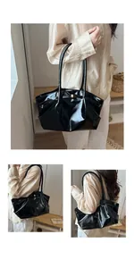 Detail of a black glossy pleated tote bag featuring a metallic bow and sleek patent leather