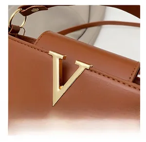 Close-up of golden V-shaped metal hardware on brown leather bucket bag with fine stitching