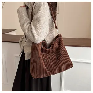 Detail view of the brown corduroy tote bag showing ribbed texture and TOTE BAG embroidery