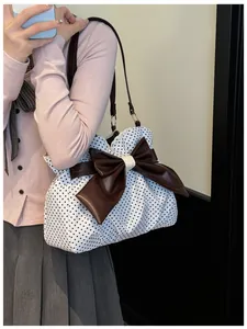Close-up detail of a white polka dot tote bag with a large brown leather bow and lace