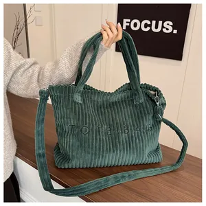 Detail of dark green corduroy tote bag showing embroidered text and premium fabric texture