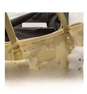 Detail of light yellow tote bag with star-moon patterns and a cloud plush pendant charm