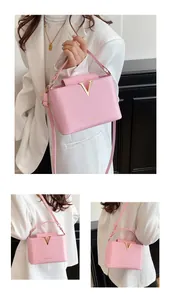 Close-up of pink faux leather crossbody bag with gold V logo and fashion text