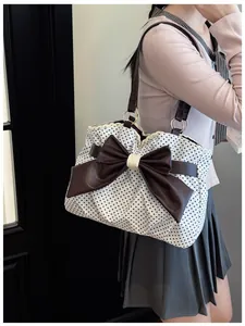 Close-up of fabric tote bag featuring black polka dots and a large brown bow detail