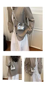 Detailed view of mini silver crescent crossbody bag with black fashion text print