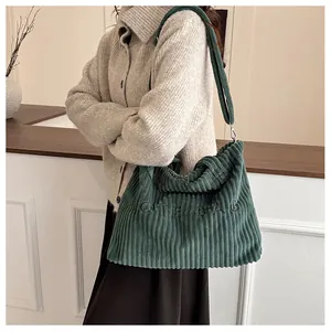 Close-up of green corduroy tote bag with TOTE BAG embroidery and adjustable strap